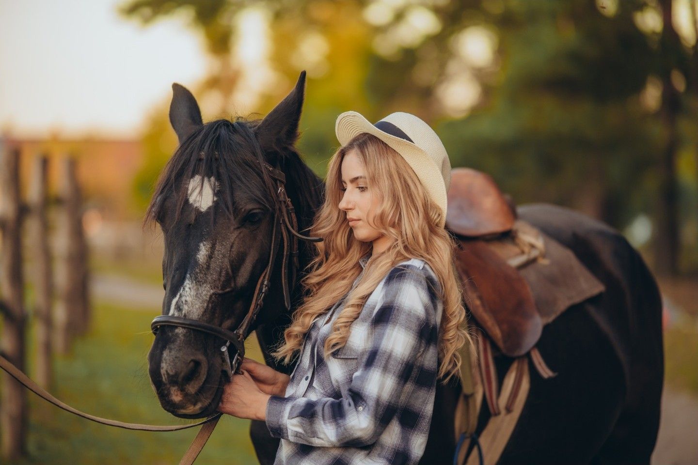 Woman standing beside a saddled bay horse.